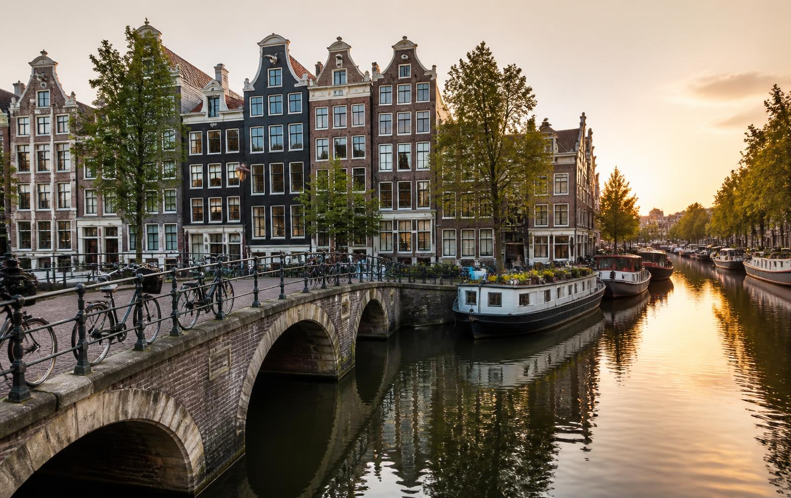 Amsterdamse grachtenpanden en brug bij zonsondergang, taxi Amsterdam met vaste prijs 24/7